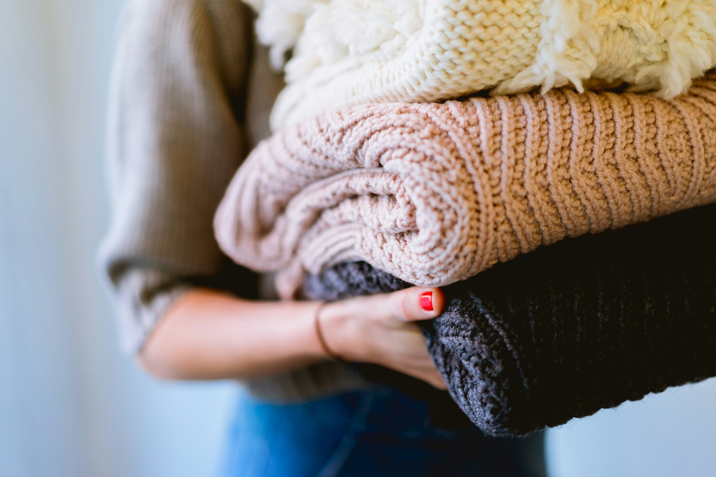 Image of woman carrying folded knitted clothes